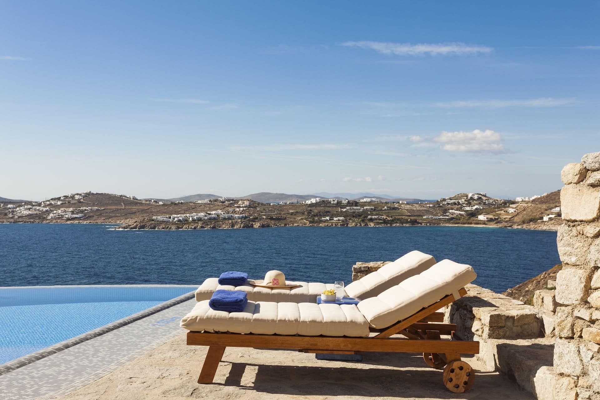 Mornings around the infinity pool during villa holidays in Mykonos with AGL overlooking the sea and Mykonos town in the background.