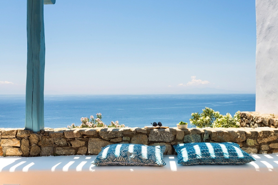 Overlooking the endless blue of the Aegean, atop the cliffs of Agios Lazaros, above one of the most quiet beaches in Mykonos.